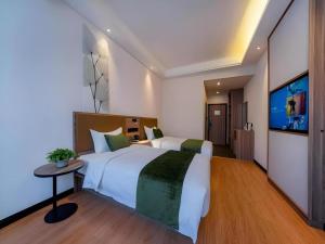 a bedroom with a large bed and a flat screen tv at GreenTree Inn Express Hebei Tangshan Guyan District Xinguang Road in Tangjiazhuang +212 photos