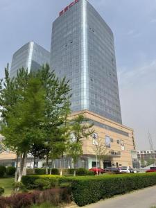 a tall building with a tree in front of it at Gya Hotel Tangshan Qian'an Fortune Center in Qian'an
