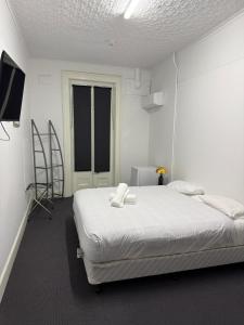 Un dormitorio blanco con una cama y un televisor. en Eatons Hotel, en Muswellbrook