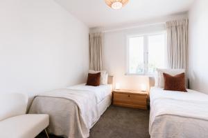 two beds in a room with a window at Tresco Apartments in Blenheim