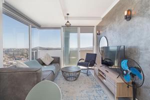 Una sala de estar con un sofá y una ventana grande. en Stylish 2-Bedroom Sea-View Apartment Horizon Bay Blouberg Beachfront, en Cape Town