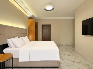 a bedroom with a white bed and a television at 利恩之家 埃及会展中心 in Cairo