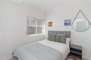 Un dormitorio blanco con una cama y un espejo. en Stylish 2-Bedroom Sea-View Apartment Horizon Bay Blouberg Beachfront, en Cape Town 13 fotos más