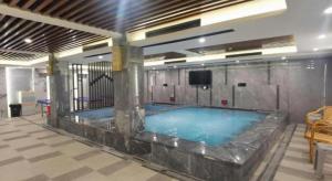 ウルムチ市にあるGreen Tree Inn Urumqi San'gong Metro Station Exitのテレビ付きの建物内の大型スイミングプール