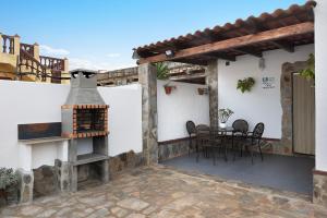 a patio with a fireplace and a table and chairs at Casa francisco in Conil de la Frontera