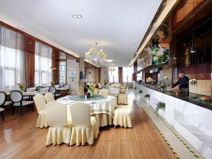 a restaurant with a table and white chairs and a bar at Vienna Hotel Henan Xinyang East Zone of Central Hospital in Pingqiao