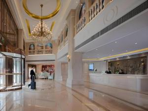 un homme debout dans un hall avec une valise dans l'établissement Vienna Hotel Guizhou Liupanshui Shuicheng Ancient Town, à Shuicheng