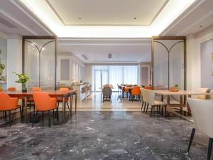 杭州市にあるVienna Hotel Hangzhou East Railway Station West Squareのダイニングルーム(テーブル、オレンジの椅子付)