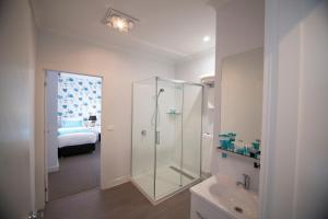 a bathroom with a shower and a sink and a bed at Beach Hotel in Burnie