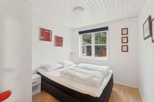 a bedroom with a bed with white walls and a window at Lovely Holiday Home By The Limfjord in Storvorde