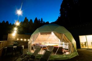 a green tent with chairs and a table and lights at フォレスタ阿蘇車帰 in Aso