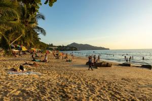 un groupe de personnes sur une plage avec l'océan dans l'établissement Cute Studio in Aristo Beach condo - 7 min walk to Surin Beach, à Surin Beach