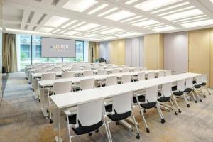 AMIGO migo Sleeping Hotel (mission hills) في Tiantangwei: غرفة كبيرة مع صفوف من الطاولات والكراسي