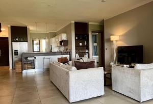 un salon avec deux canapés et une cuisine dans l'établissement Royal Park Resort & Villas, à Arsenal