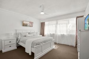 a white bedroom with a white bed and a window at Kailoha Unit 8, 27 Canberra Tce, Kings Beach in Caloundra