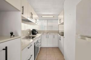 a white kitchen with white cabinets and a sink at Kailoha Unit 8, 27 Canberra Tce, Kings Beach in Caloundra