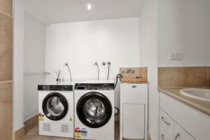 a laundry room with a washing machine and a sink at Kailoha Unit 8, 27 Canberra Tce, Kings Beach in Caloundra +2 photos