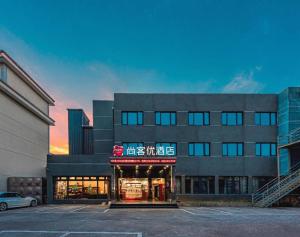 un bâtiment avec un magasin dans un parking dans l'établissement Thank Inn Hotel Zhejiang Ningbo Haishu Yinzhou Avenue Metro Station, à Ningbo