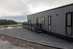 a small black building with a staircase next to it at Lodge No 147 - Stewarts Resort Cameron in Cameron