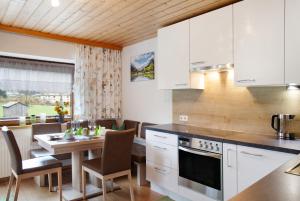 a kitchen with white cabinets and a table with chairs at Haus Bergfrieden in Au im Bregenzerwald