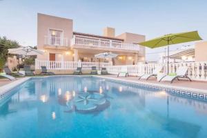a pool with chairs and umbrellas in front of a house at Can Pedra junto a Playa den Bossa in Sant Jordi