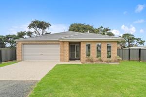 een stenen huis met een garage in een tuin bij Villa Tranquillità in Venus Bay
