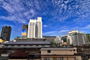 a city skyline with tall buildings and a cloudy sky at Bossotel Bangkok in Bangkok