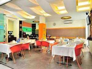 KampungdurianにあるSavali Hotelの白いテーブルと赤い椅子が備わるレストラン