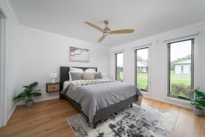 een witte slaapkamer met een bed en ramen bij Villa Tranquillità in Venus Bay