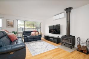 een woonkamer met een zwarte leren bank en een houtkachel bij Villa Tranquillità in Venus Bay