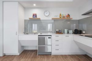 eine Küche mit weißen Schränken und einer Uhr an der Wand in der Unterkunft Large Mandogalup Family Retreat in Banjupp Station