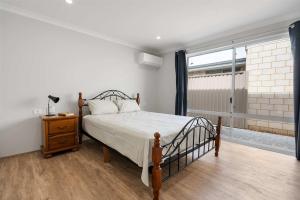 ein Schlafzimmer mit einem Bett und einem Fenster in der Unterkunft Large Mandogalup Family Retreat in Banjupp Station + 10 Fotos