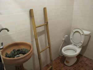 a bathroom with a toilet and a bowl of rocks at Baan Suan Phidchamika in Ban Wat Bot