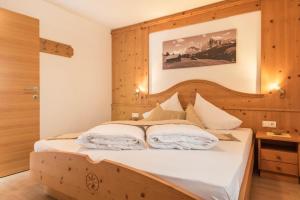 a bedroom with a bed with a wooden headboard at Kristiania Apartement Typ A1 in Siusi