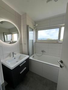 a bathroom with a sink and a tub and a mirror at Appartement nah zum Zentrum in Dornbirn