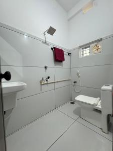 a white bathroom with a toilet and a sink at Barkka in Ponnāni