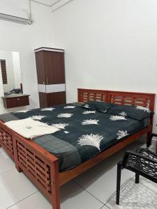 a wooden bed with a black and white blanket on it at Barkka in Ponnāni