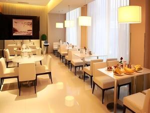 a restaurant with white tables and chairs and bananas on tables at Jinjiang Inn Dalian Jinzhou Hengda Garden in Jinzhou