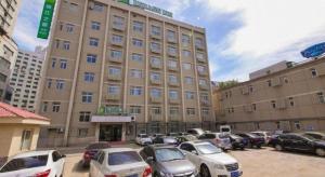 Jinjiang Inn Style Shenyang The Palace Huaiyuan Gate في شنيانغ: مبنى كبير به سيارات متوقفة في موقف السيارات