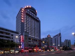 a tall building with lights on it in a city at Vienna Hotel Nanning Train Station in Nanning