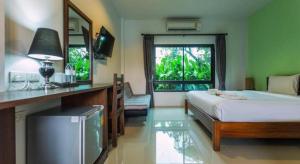 a bedroom with a bed and a desk and a window at Tamali Hotel in Ban Yuan Lae