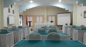a room filled with tables and chairs with a screen at Avicenna Hotel in Palangkaraya
