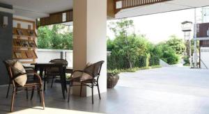 a patio with chairs and a table and a large window at Home Inn Hotel in Bangkok