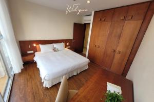 a bedroom with a large white bed and wooden cabinets at Wil'que Westlake Hotel & Residences in Hanoi