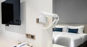 Ban Non MuangにあるXOTELのベッド、テレビ、電話が備わる客室です。