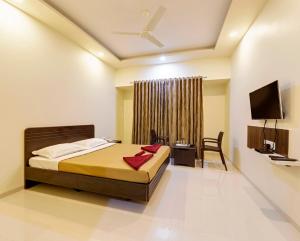 a bedroom with a bed and a desk and a television at Hotel Galaxy Inn-Best Business Hotel in Kolhapur in Kolhapur