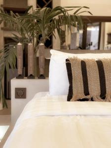 - un lit blanc avec des oreillers et des plantes en pot dans l'établissement Runik Beach Club & Resort - Adults Only, à Siquijor
