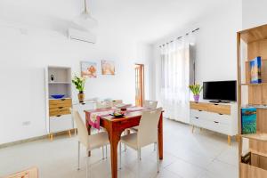 a dining room with a wooden table and white chairs at Casa Miriam in Oristano