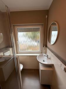 a small bathroom with a sink and a window at Modernes Apartment 1 mit eigener Küche & Bad - Schuster Homes - in Salzgitter
