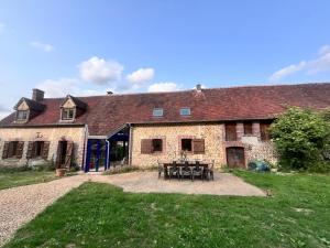 uma velha casa de pedra com uma mesa de piquenique em frente em Longère de charme, calme & piscine em Armentières-sur-Avre